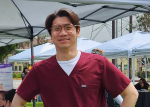 Smiling person in scrubs under outdoor tents